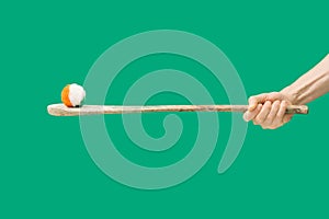 Ireland traditional sport minimal concept. Man hands holdÂ hurly sticks â€“ hurleys. Fluffy ball with Irish colors on top of it